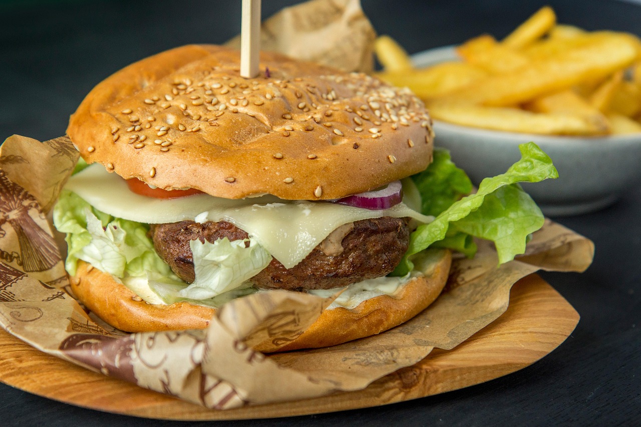 A cheeseburger on a sesame bun with fries